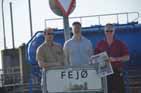 Karsten, Tom and Soren in front of Road sign/City sign for Fej� (Fejoe) - with News Paper
